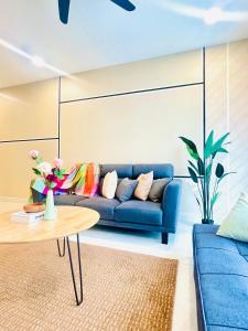 Una sala de estar con un sofá azul y una mesa. en Medini - Signature Of Cosy, en Iskandar Puteri