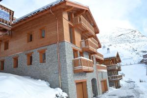 a building in the snow in front of a mountain at Chalet Le Quartz in Val Thorens