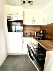 a kitchen with white cabinets and a black dishwasher at Ferienwohnung Wolkenfrei mit Pool und Sauna in Scheidegg