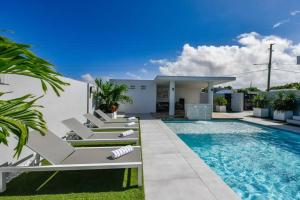 a pool with lounge chairs next to a house at NEW Luxury 5BR Villa - Casa Graziano by Bocobay in Oranjestad