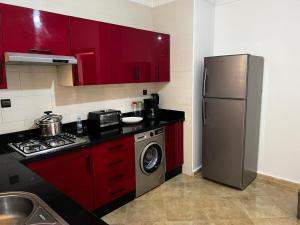 a kitchen with red cabinets and a stainless steel refrigerator at Familyconfort oujda in Oujda +29 photos