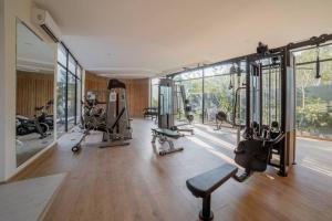 a gym with treadmills and machines in a room with windows at 2BR Designer's Pad Private Pool Closest to Beach in Tulum