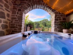 a jacuzzi tub in a stone building with a window at Les gites Romeline in Montviron