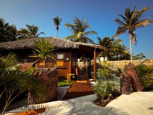 a house with a straw roof and palm trees at Alma Charme Atins in Atins