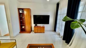 a living room with a flat screen tv on a cabinet at Le Family Palms Private Oasis with Terrace & BBQ in Playa Honda