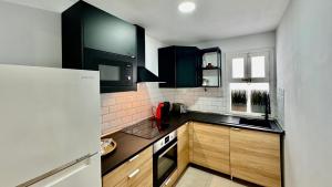 a kitchen with black cabinets and a white refrigerator at Le Family Palms Private Oasis with Terrace & BBQ in Playa Honda