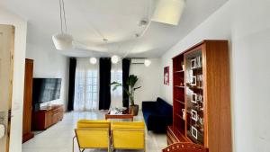 a living room with yellow chairs and a tv at Le Family Palms Private Oasis with Terrace & BBQ in Playa Honda +26 photos