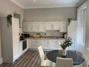 een keuken met witte kasten en een glazen tafel bij Townhouse in Belfast in Belfast +5 foto's