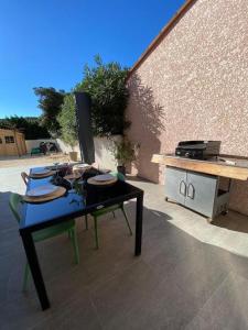 une table noire avec un grill et une table avec des chaises dans l'établissement La contemporaine 2 chambres à Ste Marie, à Sainte-Marie-la-Mer