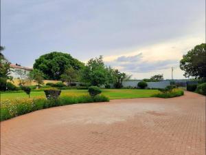 ヨハネスブルグにあるFairlands Luxury Apartmentsの花と木々が生い茂る公園のレンガの道