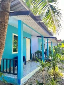 a blue house with a wooden porch with a palm tree at Lanta bluewave Bungkalow in Phra Ae beach