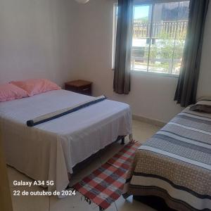 a bedroom with two beds and a window at Aconchego do peró in Cabo Frio