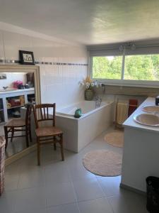 ein Badezimmer mit einer Badewanne, einem Stuhl und einem Waschbecken in der Unterkunft Appart 6 couchages en plein cœur de village in Neauphle-le-Château