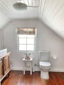 a white bathroom with a toilet and a window at The Town House - Lower Knysna Central in Knysna