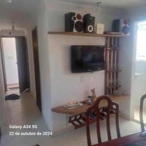 a living room with a table and a tv on a wall at Aconchego do peró in Cabo Frio