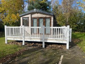 a white fence in front of a small cabin at Luxurious 2 Bedroom Caravan in Longniddry