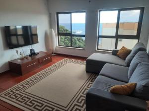 a living room with a couch and a flat screen tv at Populo Beach Apartment in São Roque