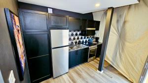 a kitchen with black cabinets and a white refrigerator at Dôme Le rocher in Brownsburg