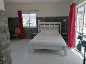 a bedroom with a bed and a red curtain at STUDIO VUE MER - CASA da LUZ in Mindelo