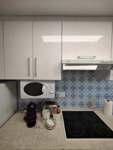 a kitchen with white cabinets and a stove top oven at Precioso apartamento residencial con vistas al mar in Puebla de Farnals