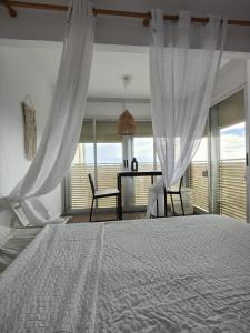 a bedroom with a white bed and a table and chairs at Precioso apartamento residencial con vistas al mar in Puebla de Farnals