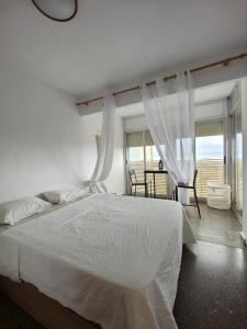 a bedroom with a white bed and a large window at Precioso apartamento residencial con vistas al mar in Puebla de Farnals