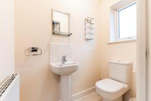 a white bathroom with a toilet and a sink at Black Brick Stays, Great Location, Free Parking, Fast Wi-Fi, Families & Contractors Welcome in Peterborough +13 photos