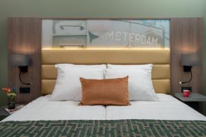 a bedroom with a large bed with white pillows at Leonardo Royal Hotel Amsterdam in Amsterdam