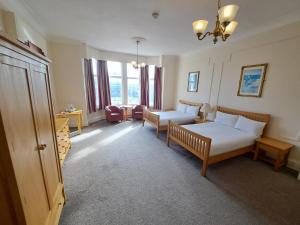 a bedroom with two beds and a couch and a chair at Scarisbrick Hotel in Southport