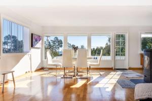 a living room with a table and chairs and windows at Koselig hus rett ved stranda,nydelig & ferierende! in Grimstad