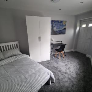 a bedroom with a bed and a desk next to a door at A luxury 2 bed flat in Romford in Romford