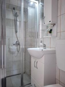 a white bathroom with a sink and a shower at Studio apartman Mirta II in Varaždin