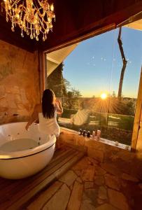 een vrouw in een bad in een kamer met een raam bij Pousada Villa Dolce Amore - Boutique Hotel in Campos do Jordão