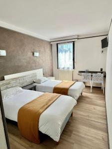 マイエンヌにあるHôtel La Tour des Anglaisのベッド3台とテーブルがあるホテルの部屋 +33枚の写真