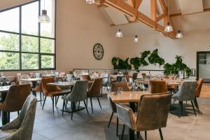 Un restaurante con mesas y sillas y un reloj en la pared. en Hotel Le Belmont, en Belmont-Tramonet