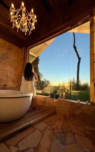 a woman sitting in a bath tub looking out a window at Pousada Villa Dolce Amore - Boutique Hotel in Campos do Jordão