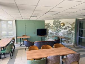a dining room with tables and chairs and a tv at Hôtel La Pierre Bleue in Saint-Gildas-de-Rhuys