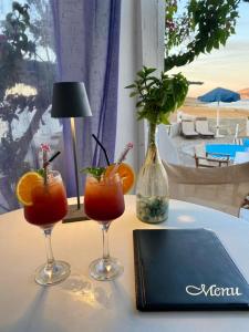 a table with two cocktails and a laptop on it at Anatoli Studios in Skhoinoussa