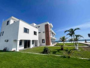 a white house with palm trees and the ocean at Villa Monterrico in La Muerte