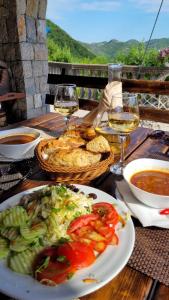 a table with a plate of food and glasses of wine at Skadar Lake Family Resort in Rijeka Crnojevića