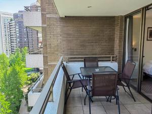 Un patio con sillas y una mesa en un balcón. en Apart Barrio El Golf con piscina, en Santiago