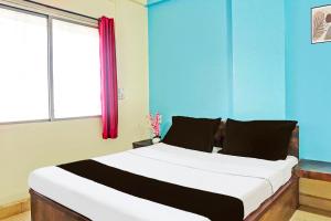 a bedroom with a large white bed with a window at Hotel O Happy Lodging in Pune
