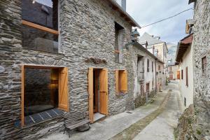 un antico edificio in pietra con porte in legno su una strada di Era Artiga by FeelFree Rentals a Les Bordes