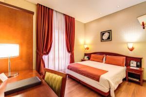 a hotel room with a bed and a desk with a desk at Augusta Lucilla Palace in Rome