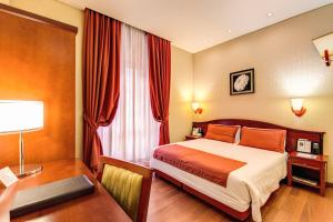 una camera d'albergo con letto e scrivania con scrivania di Augusta Lucilla Palace a Roma