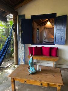 a room with a bench with red pillows and a table at Casa Botanique Jungle Loft in Abraão