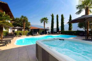 a swimming pool with an umbrella and palm trees at Residence Untermösslhof - La Villa in Lana