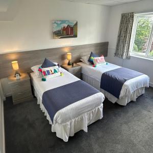 two beds in a hotel room with two lamps at Westhill Country Hotel in Saint Helier Jersey