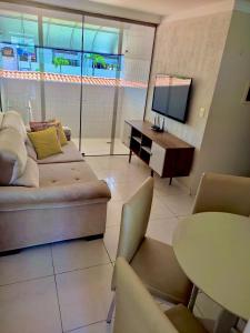 a living room with a couch and a tv and a table at Suites Tropical in João Pessoa