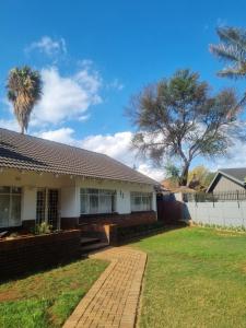 a house with a palm tree and a fence at Jazreel b&b in Vanderbijlpark